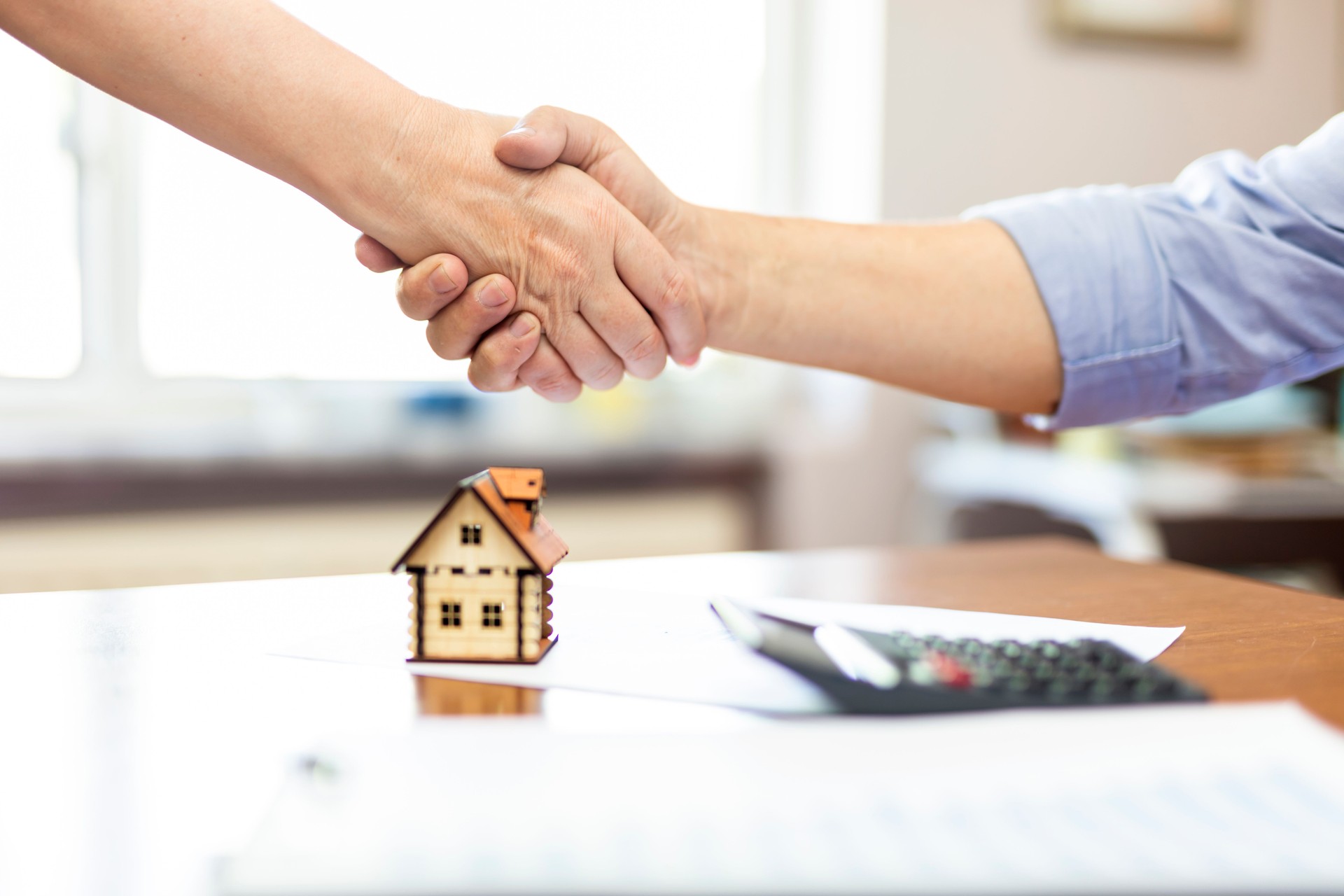 Real estate agent and customers shaking hands together celebrating finished contract